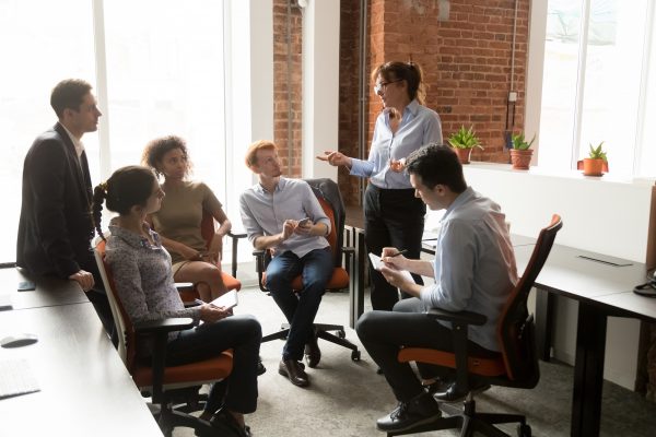 Group of people sitting in a circle with a woman leading the dialogue.