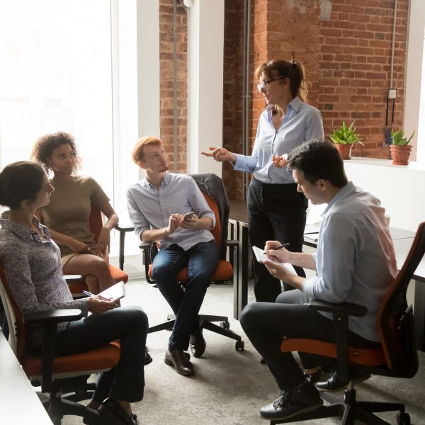 Group of people sitting in a circle with a woman leading the dialogue.